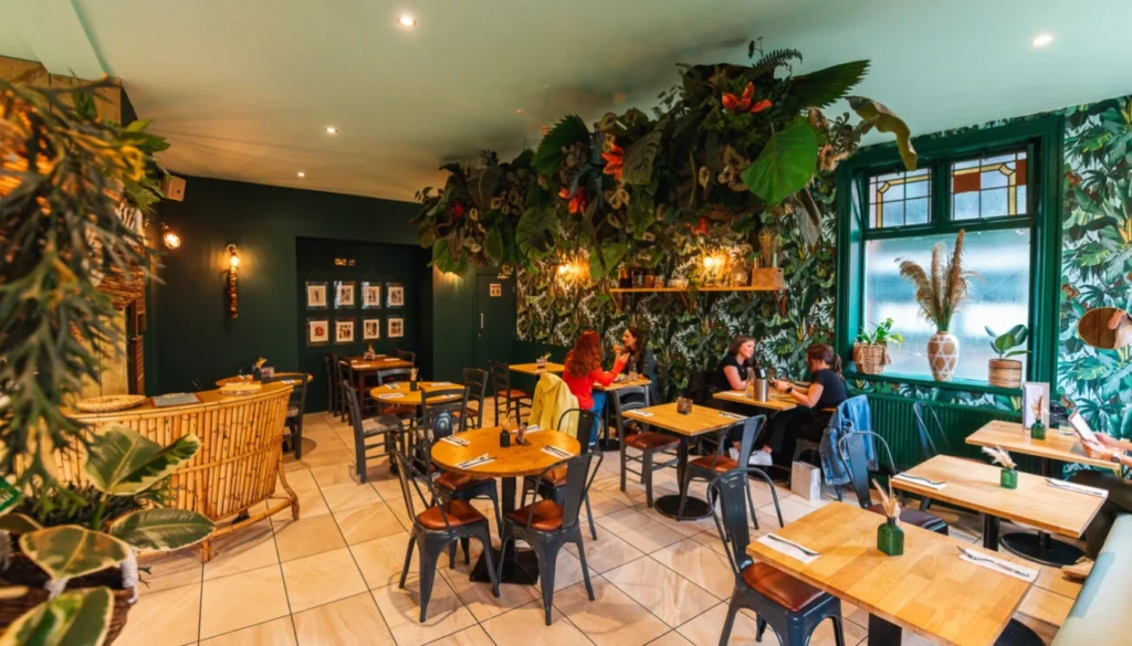 Exterior view of a vegetarian restaurant Manchester with outdoor seating and plants.